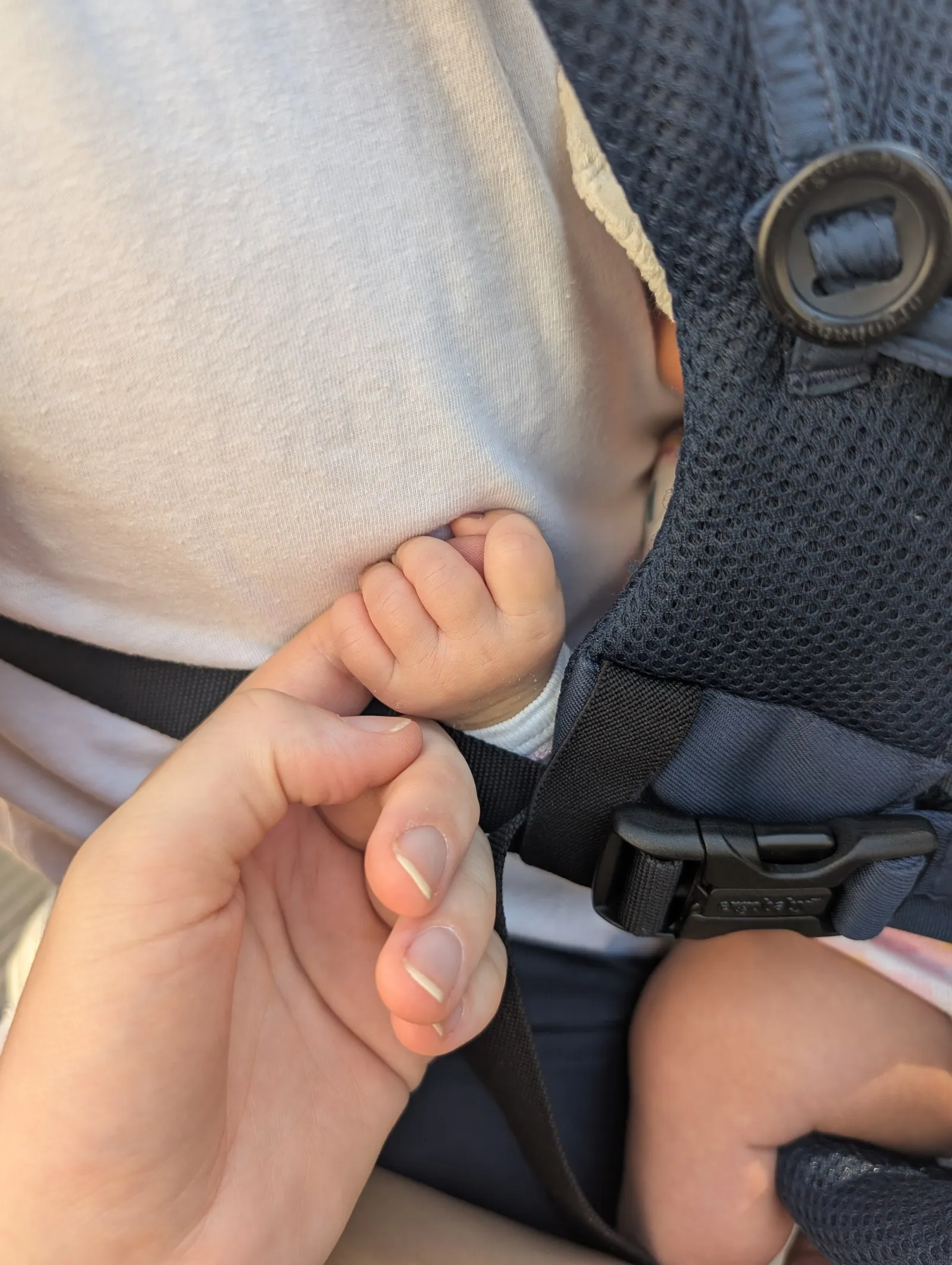 La main d’un bébé dans un porte-bébé